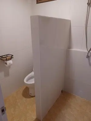 a bathroom with a toilet in a white room at Pradu House Koh Yao Noi in Ko Yao Noi