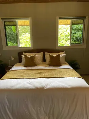 a large bed in a bedroom with two windows at Pradu House Koh Yao Noi in Ko Yao Noi