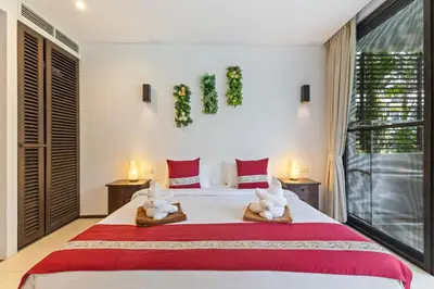 a bedroom with a large bed with towels on it at Bangtao Beach Gardens - Pool & Garden View Apartment in Surin Beach