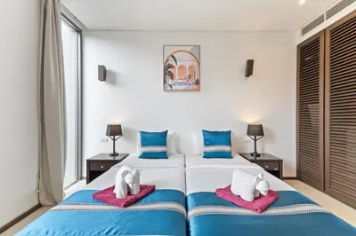 a bedroom with two beds with blue and white at Bangtao Beach Gardens - Pool & Garden View Apartment in Surin Beach