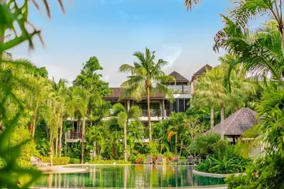 an exterior view of a resort with a pool and palm trees at Bangtao Beach Gardens - Pool & Garden View Apartment in Surin Beach