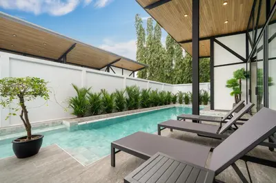 an outdoor swimming pool with two chairs and a table at NEW! Sleek Design Oxygen Pool Villa 3 BR - Sunset Garden 14 in Ban Saiyuan (1)