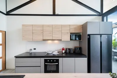 a kitchen with white cabinets and a black refrigerator at NEW! Sleek Design Oxygen Pool Villa 3 BR - Sunset Garden 14 in Ban Saiyuan (1)