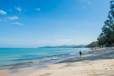 a person walking on a beach next to the ocean at Bangtao Beach Tropical Holiday Retreat in Bang Tao Beach