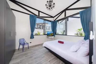 a bedroom with a bed and a blue chair at Stylish Eco Villa Sunset Garden 1E with Private Pool near Nai Harn Beach in Ban Saiyuan (1)