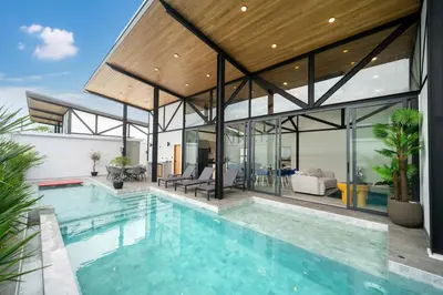 an indoor pool in a house with glass walls at Stylish Eco Villa Sunset Garden 1E with Private Pool near Nai Harn Beach in Ban Saiyuan (1)