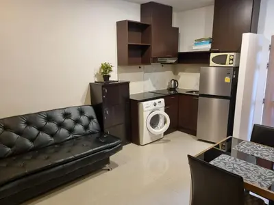 a living room with a couch and a kitchen at Karon Chic Seashore Apartment in Karon Beach