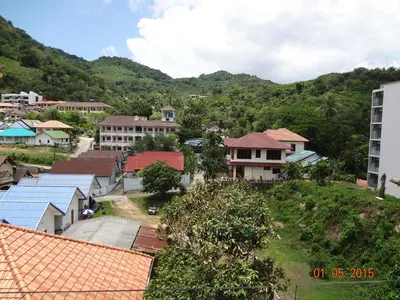 a village with houses and mountains in the background at Karon Chic Seashore Apartment in Karon Beach