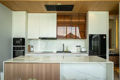 a kitchen with white cabinets and a black refrigerator at Mouana Residence Song Khun Chalong 4-bedroom Pool Villa 896 in Chalong
