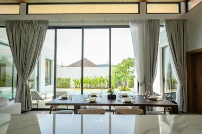 a dining room with a table and chairs and large windows at Mouana Residence Song Khun Chalong 4-bedroom Pool Villa 896 in Chalong