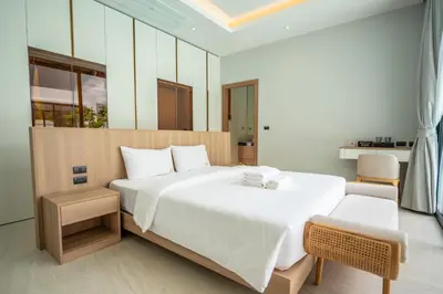 a bedroom with a large white bed and a chair at Mouana Residence Song Khun Chalong 4-bedroom Pool Villa 896 in Chalong