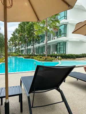 a chair and an umbrella next to a swimming pool at La Vita Rawai Nai Harn Beach 5 Star 1 BDR in Rawai Beach