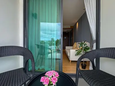 a room with two chairs and a table with flowers on it at La Vita Rawai Nai Harn Beach 5 Star 1 BDR in Rawai Beach