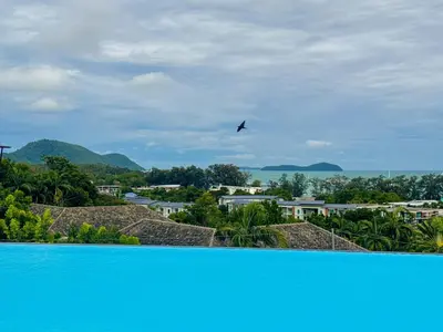 a bird flying in the sky over a blue pool at La Vita Rawai Nai Harn Beach 5 Star 1 BDR in Rawai Beach