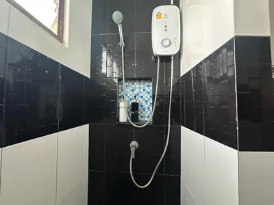 a shower in a black and white tiled bathroom at By the Beach Hostel in Phi Phi Don