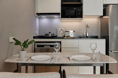 a kitchen with a table with two plates and wine glasses at Title Legendary, 1-BR, 45 sqm, 8 min to BangTao Beach in Bang Tao Beach