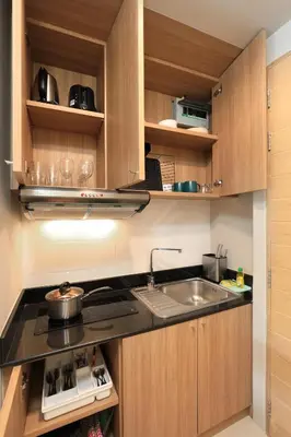 a kitchen with wooden cabinets and a sink at Spacious studio with access to the pool in Karon Hill condo in Karon Beach