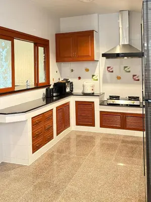 a kitchen with wooden cabinets and a stove top oven at RisaVilla Phuket - 4BR Pool Villa near Patong Beach in Patong Beach
