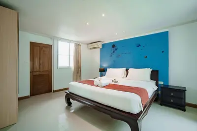 a bedroom with a large bed with a blue wall at Number Nine Pool Villa in Ban Tha Rua