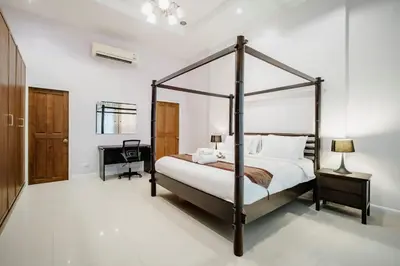 a bedroom with a four poster bed and a desk at Number Nine Pool Villa in Ban Tha Rua
