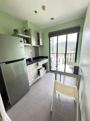 a kitchen with a refrigerator and a table with a chair at The Base Height in Phuket Town