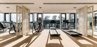 a gym with treadmills and ellipticals in a room with windows at The Base Height in Phuket Town