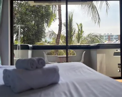 a bedroom with a bed and a large window at NR Nanai Patong in Patong Beach