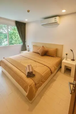 a bedroom with a large bed with a fan on the wall at Relaxing Apartment in Karon in Karon Beach