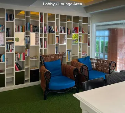 a library with two chairs and bookshelves at Stay Kata in Kata Beach