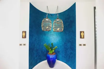 a blue wall with a blue vase and two bird cages at Stay Kata in Kata Beach