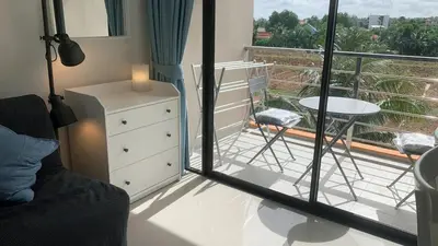a bedroom with a balcony with a table and a chair at Cozy studio Sunset view near of MaiKhao beach in Ban Mai Salae