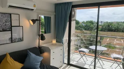 a living room with a couch and a balcony at Cozy studio Sunset view near of MaiKhao beach in Ban Mai Salae