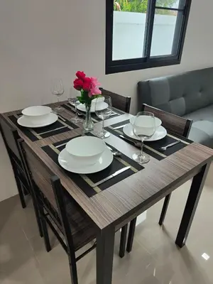 a dining room table with plates and a vase of flowers at The White House Chalong in Chalong