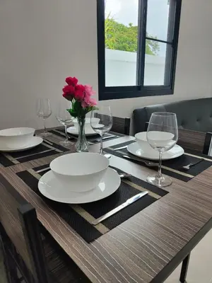 a wooden table with plates and glasses and a vase of flowers at The White House Chalong in Chalong