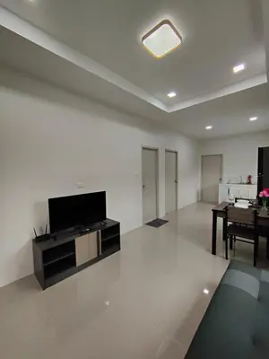 a living room with a television and a table at The White House Chalong in Chalong