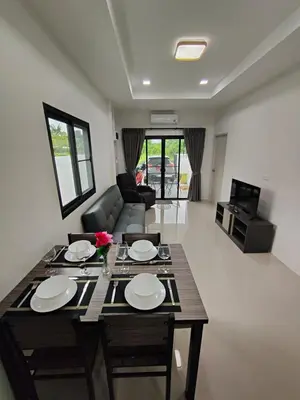 a living room with a table and a couch at The White House Chalong in Chalong