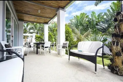 a porch with white chairs and a table and trees at Villa with private pool in Kamala in Kamala Beach