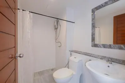 a white bathroom with a toilet and a sink at Baan KetKaew Patong in Patong Beach