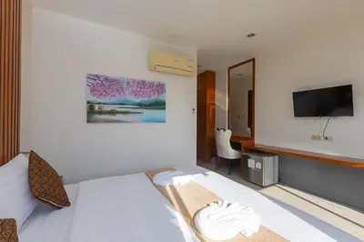 a hotel room with a bed and a flat screen tv at Baan KetKaew Patong in Patong Beach