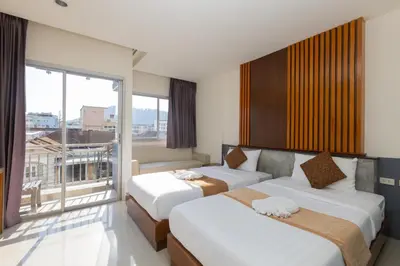 a hotel room with two beds and a large window at Baan KetKaew Patong in Patong Beach