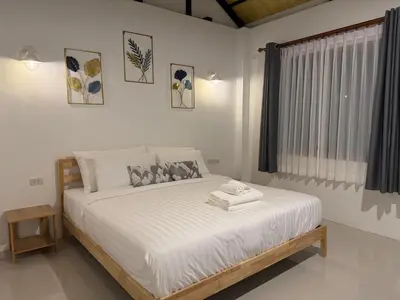 a bedroom with a bed with white sheets and a window at Sea Escape Koh Yao Yai in Ko Yao Yai