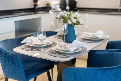 a table with blue chairs and a blue vase with flowers at The Title Legendary Condo with a large terrace 308 in Bang Tao Beach