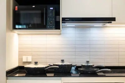 a kitchen with three pots on a stove with a microwave at The Legendary Apartment 408 in Bang Tao Beach