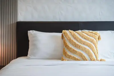 a bed with white pillows and a brown and white pillow at Platinum Villa Rawai 76 in Rawai Beach