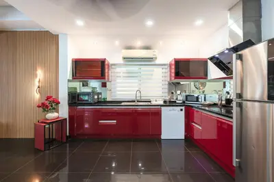 a kitchen with red cabinets and a stainless steel refrigerator at Platinum Villa Rawai 76 in Rawai Beach