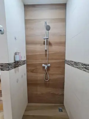 a shower in a bathroom with a wooden wall at 41 квадратный метр, апартамент на пляже Сурин in Surin Beach