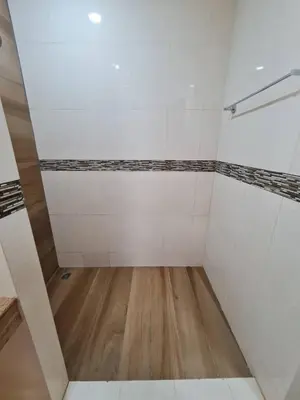 an empty room with white tiles and a wooden floor at 41 квадратный метр, апартамент на пляже Сурин in Surin Beach