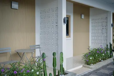 a building with a table and chairs and flowers at The Cozy Haus Airport in Ban Muang Mai (1)