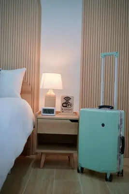 a bedroom with a bed and a suitcase on a night stand at The Cozy Haus Airport in Ban Muang Mai (1)