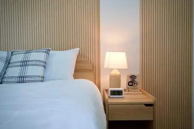 a bedroom with a bed and a clock on a night stand at The Cozy Haus Airport in Ban Muang Mai (1)
